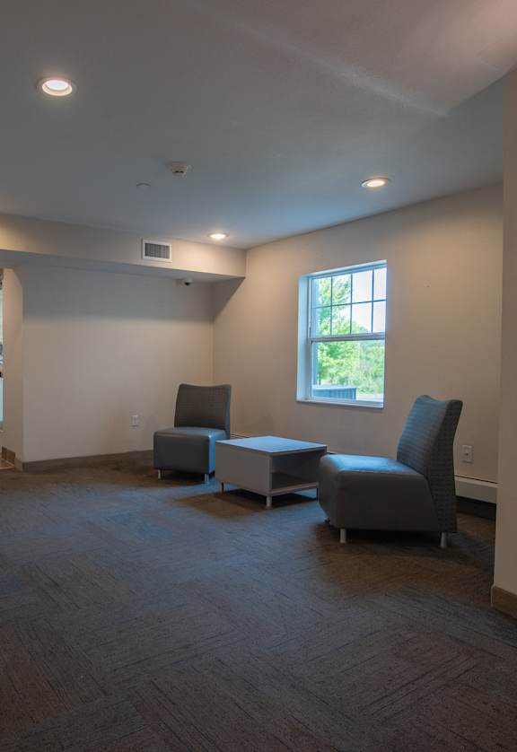 an empty living room with chairs and a table and a bathroom