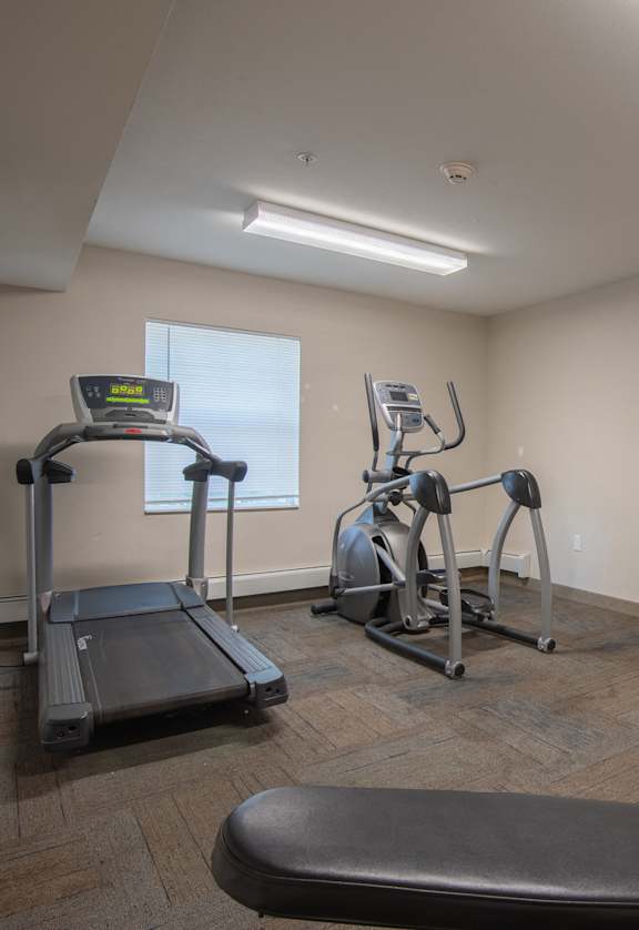 a gym with treadmills and weights in the corner of a room