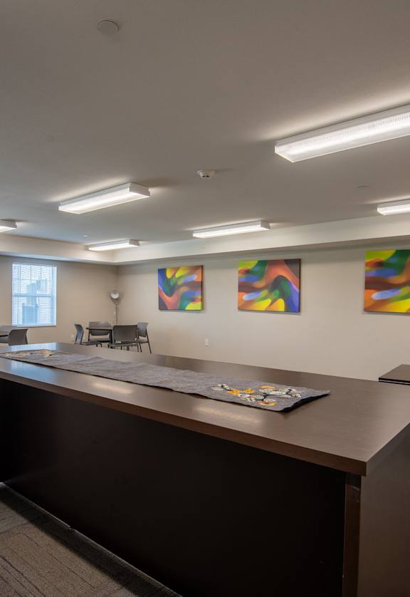 a conference room with a long table and chairs and paintings on the wall