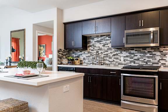 A modern kitchen with a stainless steel oven and black cabinets.
