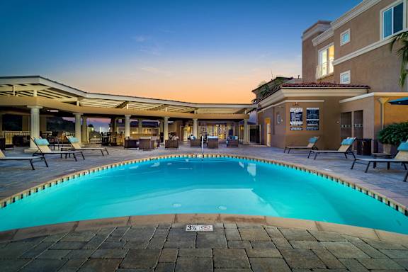 A swimming pool surrounded by lounge chairs and umbrellas.