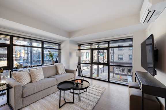 A living room with a grey couch, a black coffee table, and a flat screen TV.