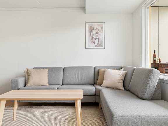 A grey couch with a wooden table in front of it.