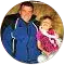 A man in a blue jacket holds a little girl in a pink dress.