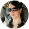 A woman with sunglasses and a brown jacket.