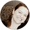 A woman with brown hair and a white shirt is smiling.
