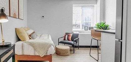 A bedroom with a bed, desk, chair, and a window.