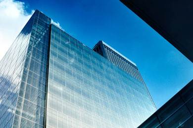 A tall glass building stands under a blue sky.