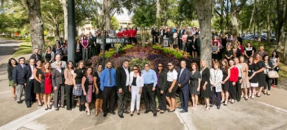 a group of people standing in front of a flower garden