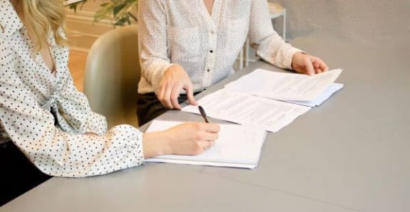 two people sitting at a table with papers
