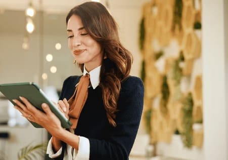 A woman in a black sweater is holding a tablet.