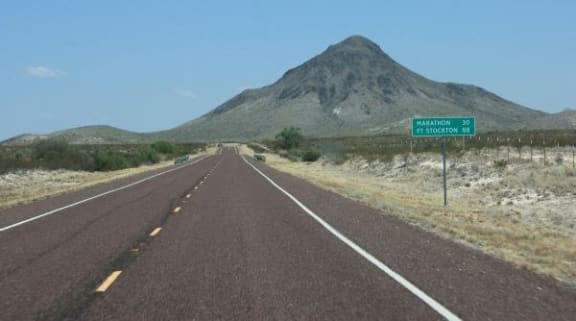 a road with a mountain and a road sign