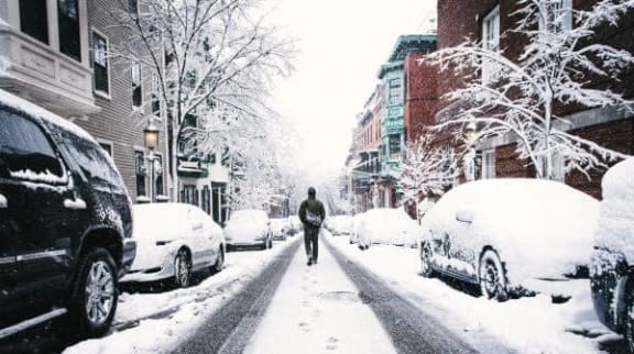 a man is walking down a snow covered street