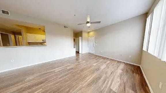 an empty living room with a wood floor and a ceiling fan at The Paseo by Picerne, 85395