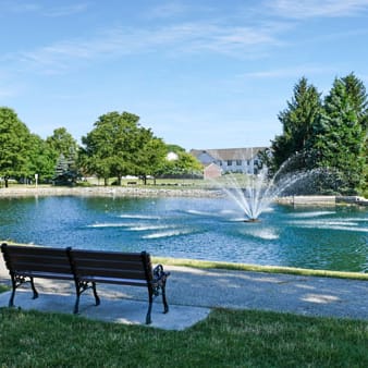 a park bench sitting in front of a water fountain
