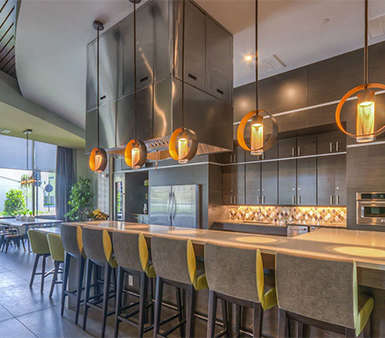 A modern kitchen with a long bar and hanging lights. at The Strand, Florida