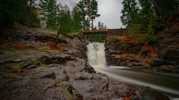 a waterfall flowing under a bridge