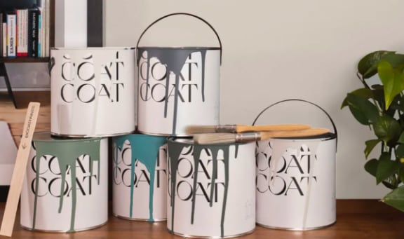 a group of metal canisters sitting on a shelf next to a plant