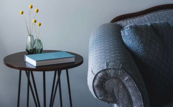 a book and a vase on a table next to a bed