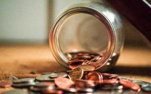 a jar with coins spilling out of it on a table