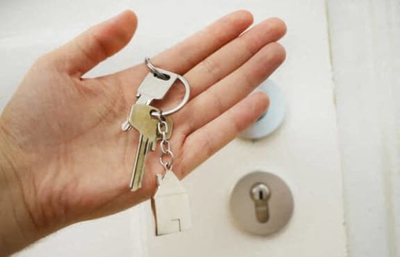 a hand holding a set of keys in front of a door