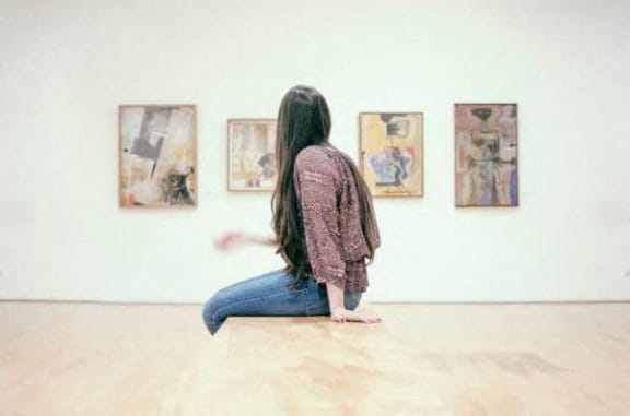 a woman sitting on the floor in front of paintings