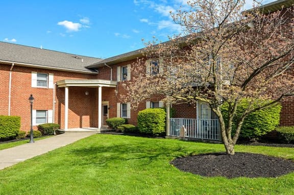 a red brick house with a tree in front of it