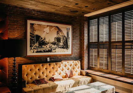 A room with a tufted sofa and a framed picture on the wall.