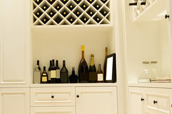 A wine rack with several bottles of wine on a cabinet.