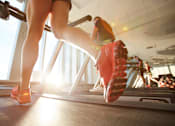 Thumbnail 3 of 6 - A person is running on a treadmill in a gym.