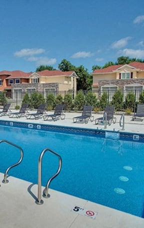 a swimming pool with chairs around it and some apartments in the background at The Residences at Toscana Park, Granger, Indiana