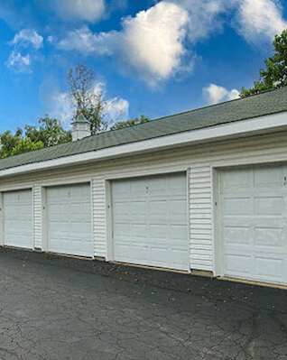 A row of white garage doors in front of a building.
