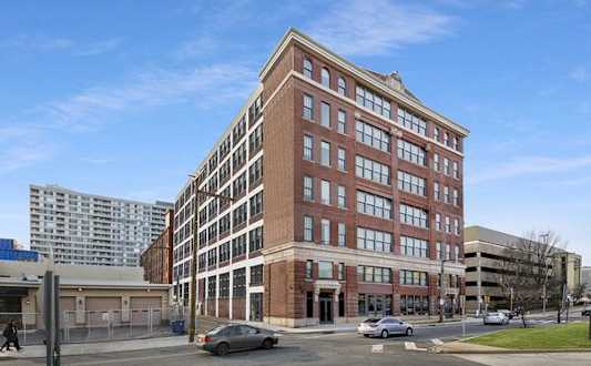 A large red brick building with many windows sits on a street corner.