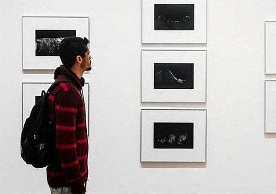 a man is looking at pictures on a wall