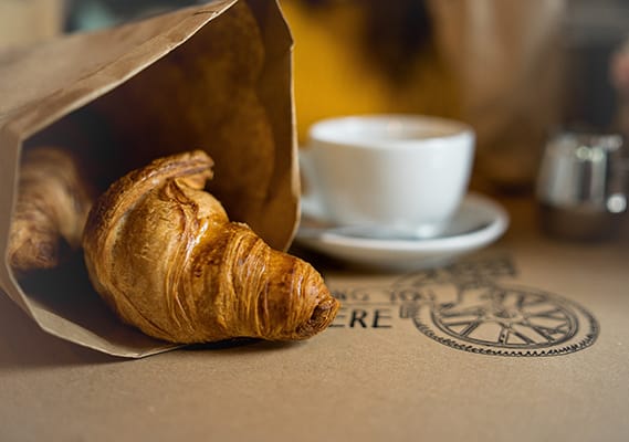 a croissant and a cup of coffee on a table
