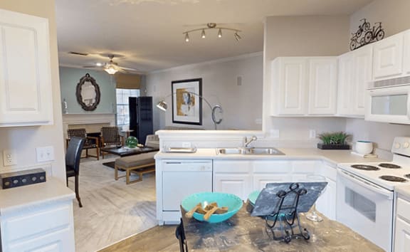 an open kitchen and living room with white cabinets and a table