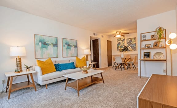 a living room with a white couch and yellow and blue pillows