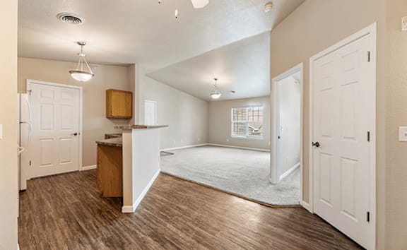 A spacious living room with a wooden floor and white walls.