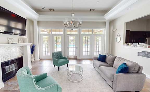 A living room with a grey couch, a green chair and a fireplace.
