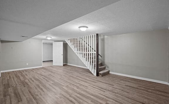 an empty living room with a staircase and wood flooring