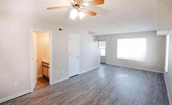 A room with a ceiling fan and wooden flooring.