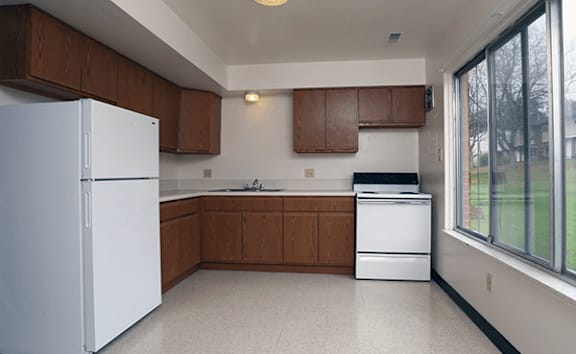 A kitchen with white appliances and brown cabinets.