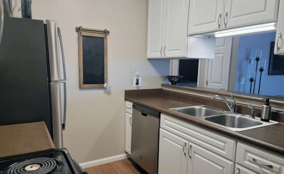 A kitchen with a black fridge and white cabinets.