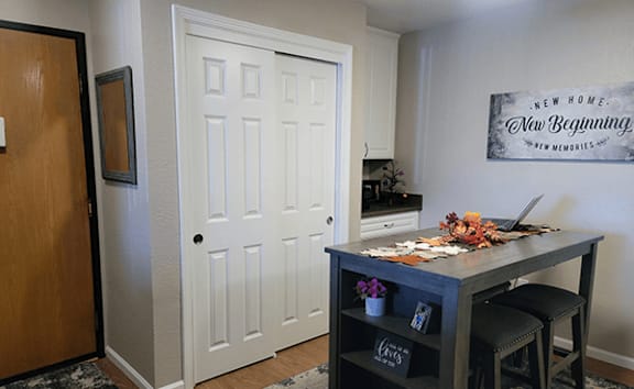 A room with a white door and a black table with a laptop on it.