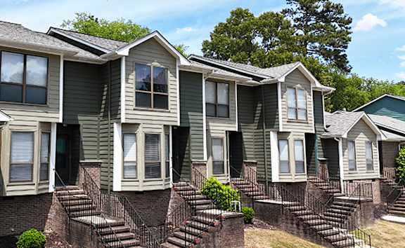 A row of houses with green siding and white trim.