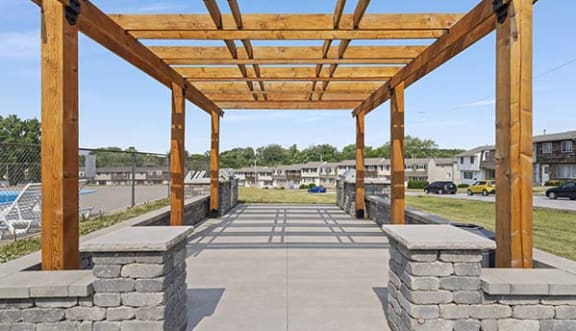 a covered area with stone pillars and a wood roof
