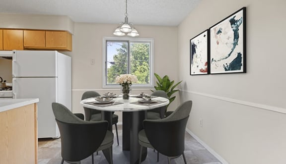 a dining room with a table and chairs and a kitchen in the background