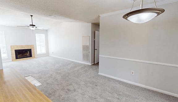 A large, empty room with a fireplace and a ceiling fan.