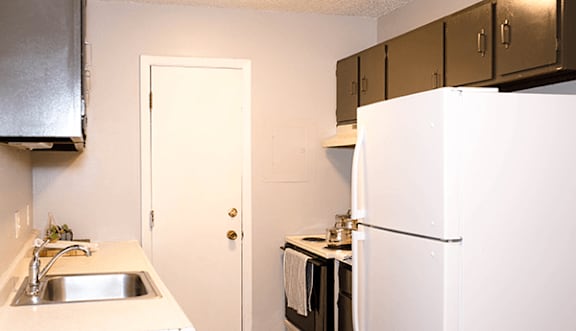 A kitchen with a sink, refrigerator, and cabinets.