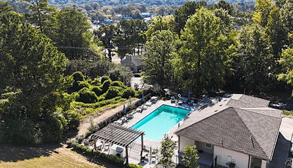 an aerial view of a swimming pool surrounded by trees
